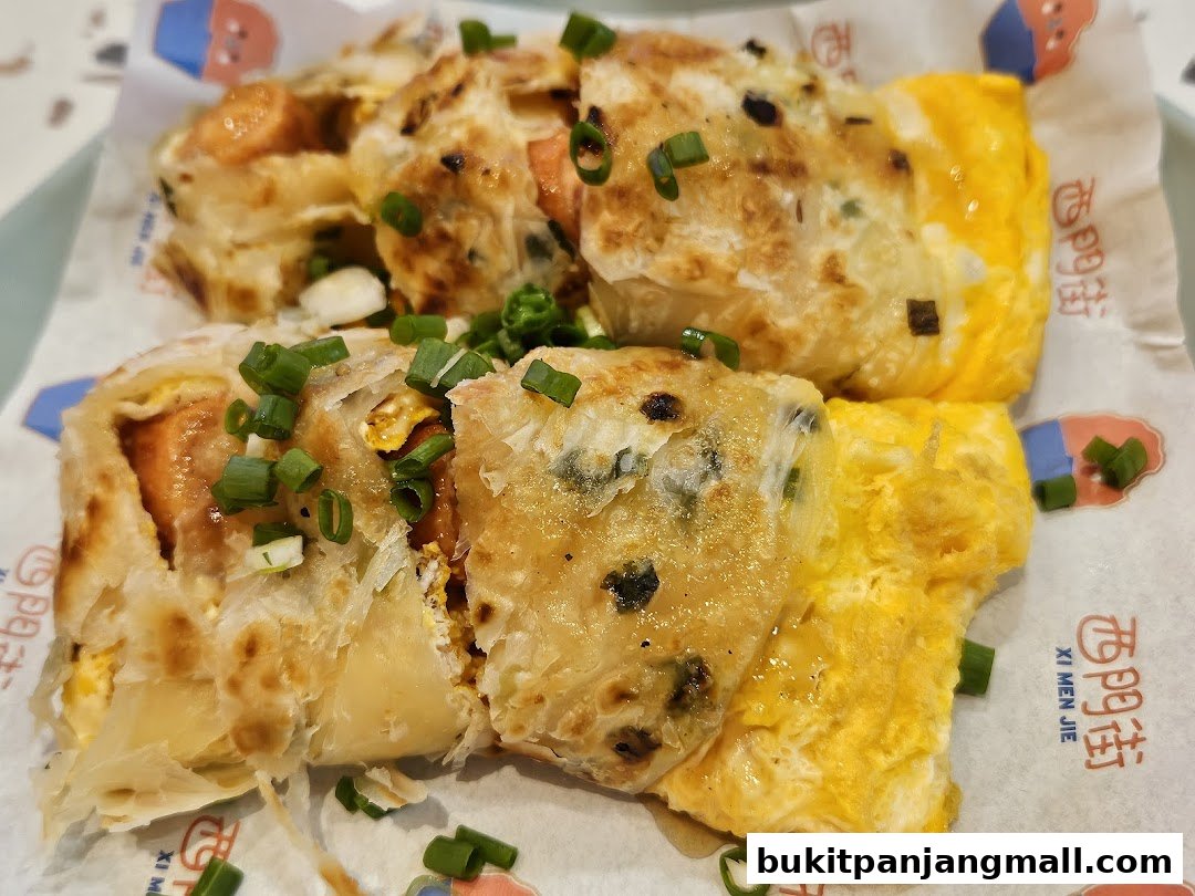 Close-up of Taiwanese scallion pancakes with egg and sausage, garnished with chopped green onions.