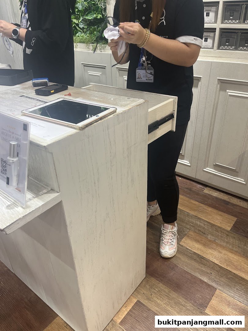 Staff members at OWNDAYS Bukit Panjang Plaza cleaning glasses and attending to a counter.