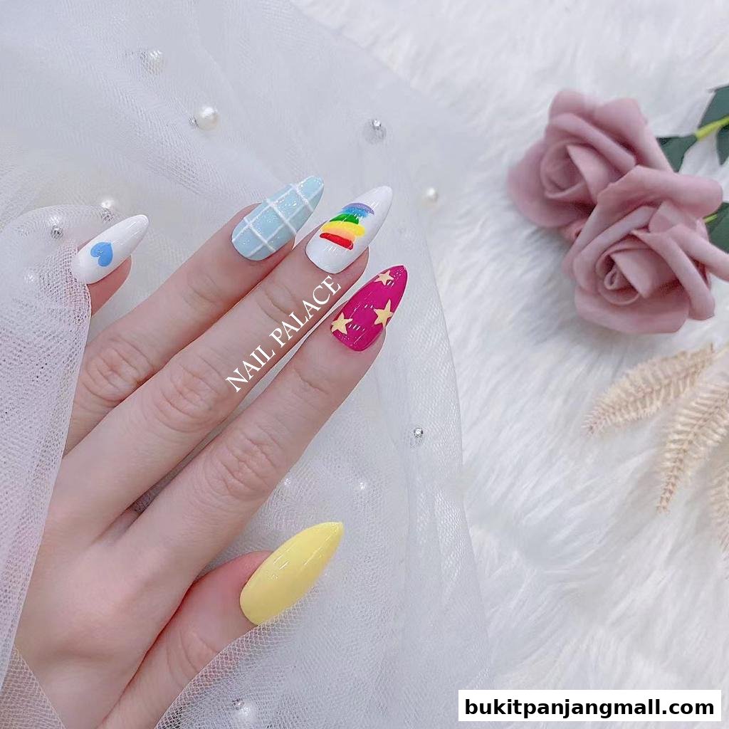 A hand with creatively designed nails, featuring a rainbow, grid, and stars.