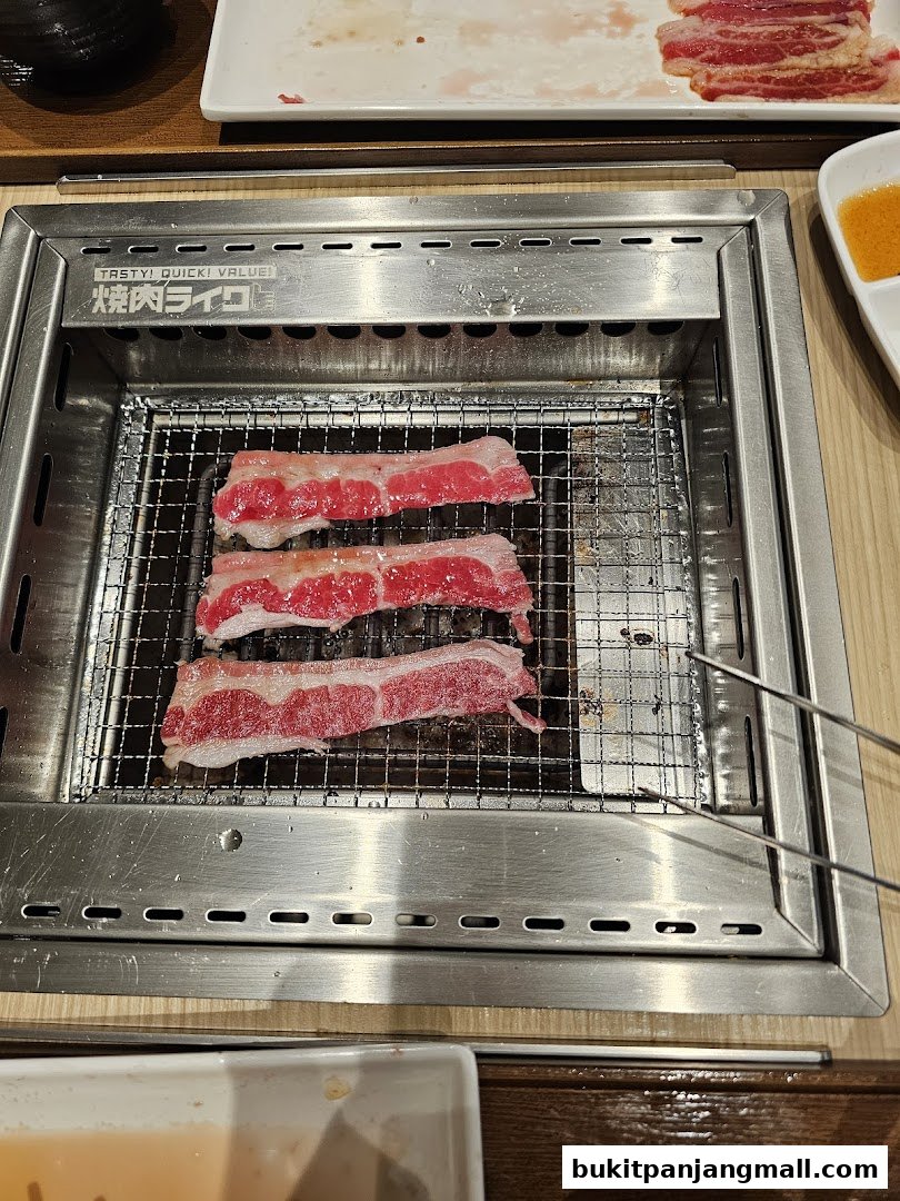 Sizzling slices of beef are grilled on a metal grate at Yakiniku Like.