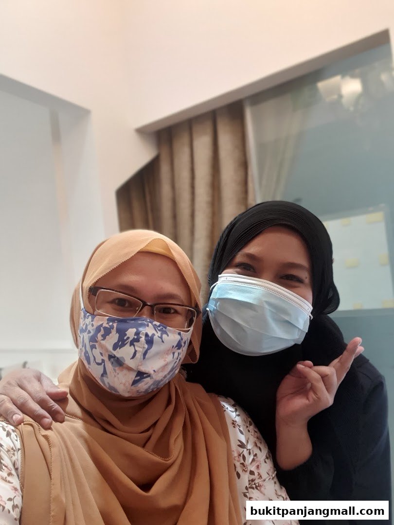 Two women wearing face masks pose for a selfie in a salon.