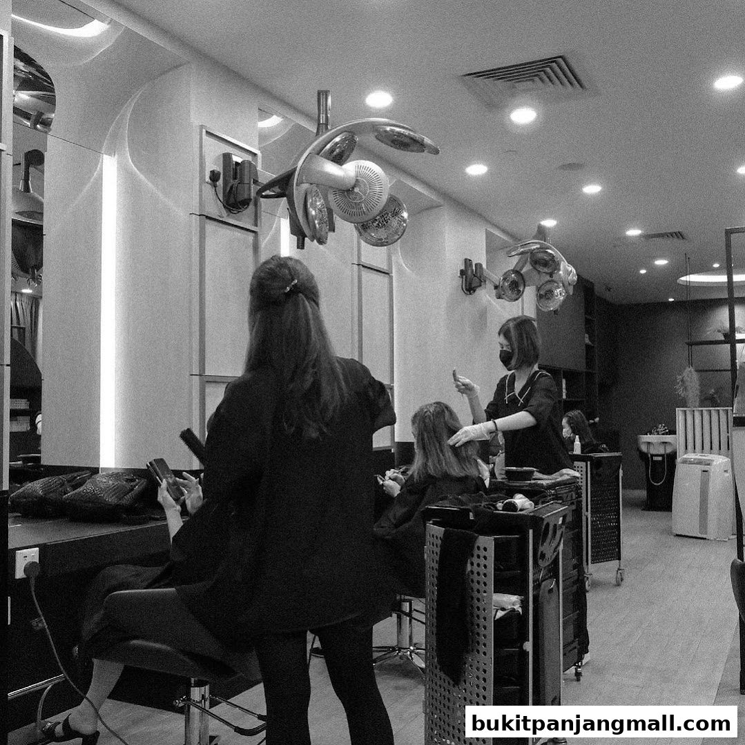 Hairdressers working on clients inside a modern salon with drying lamps.