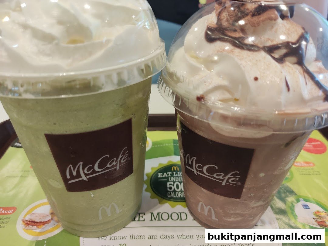 Two McCafe drinks, one green and one chocolate, topped with whipped cream.