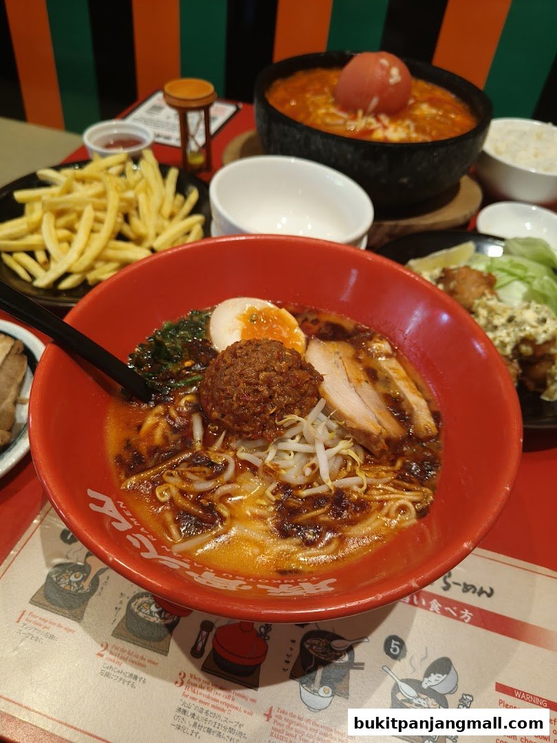 A close-up of a steaming bowl of ramen with pork, egg, and sprouts, served with fries and another dish.