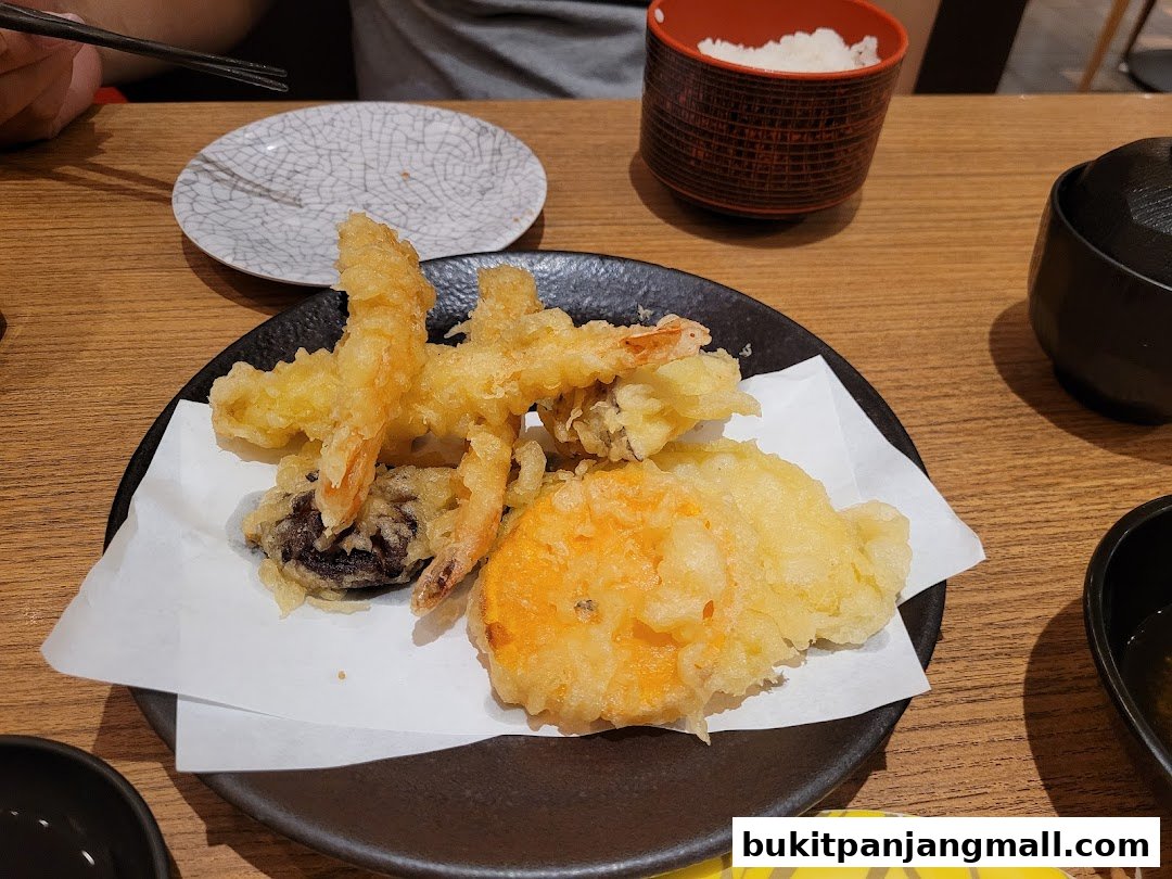 A plate of assorted tempura, including shrimp, mushroom, and sweet potato, served with rice and soup.