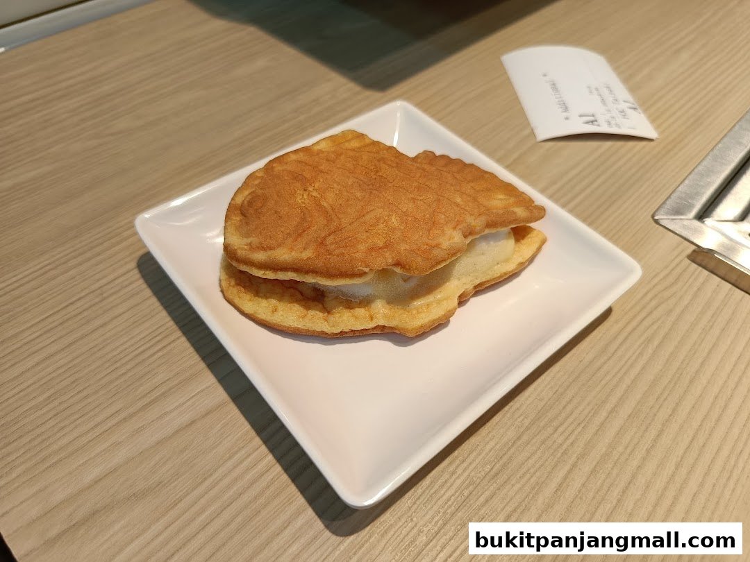 A fish-shaped pancake filled with cream served on a white plate.