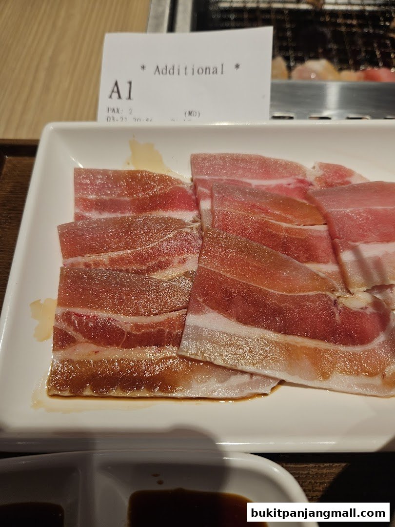 A plate of thinly sliced raw pork belly with a side of dipping sauce.