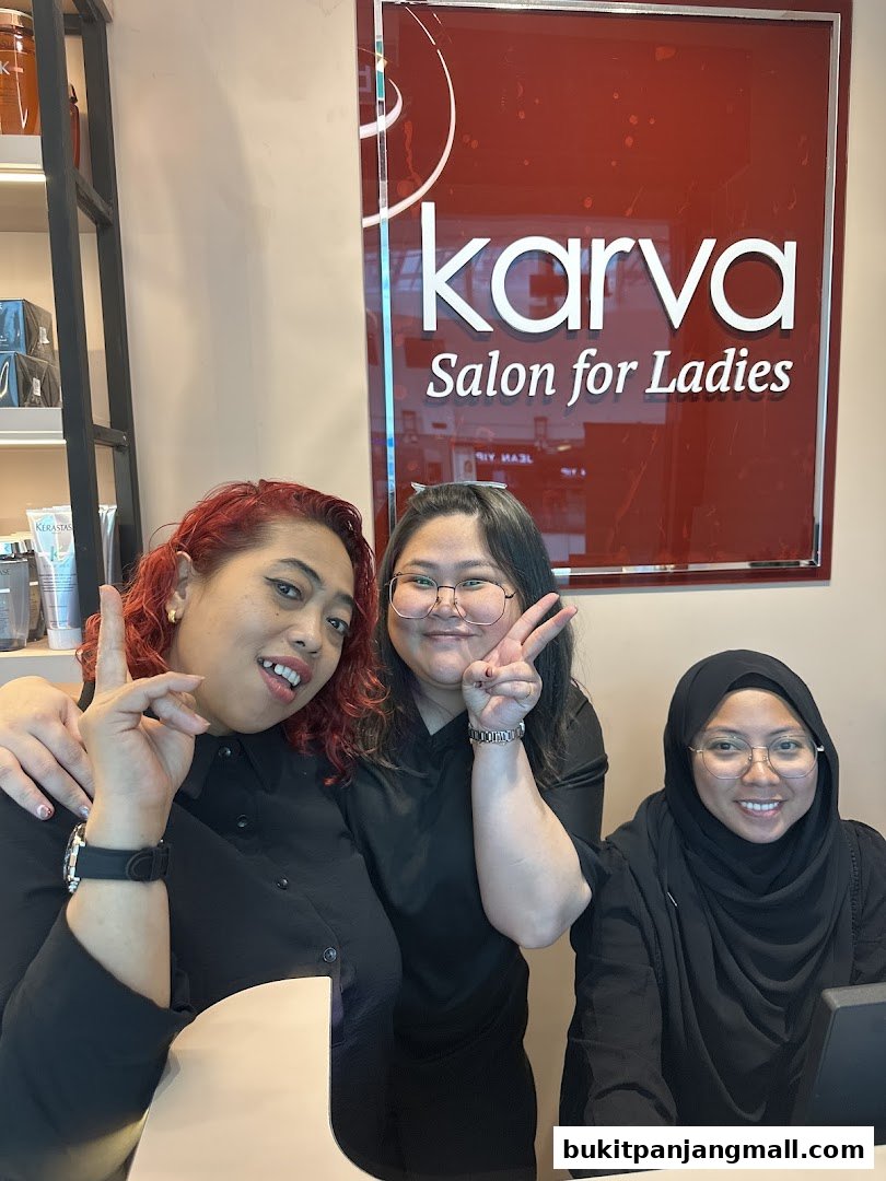 Three smiling women in black shirts pose in front of the KARVA Salon for Ladies sign.