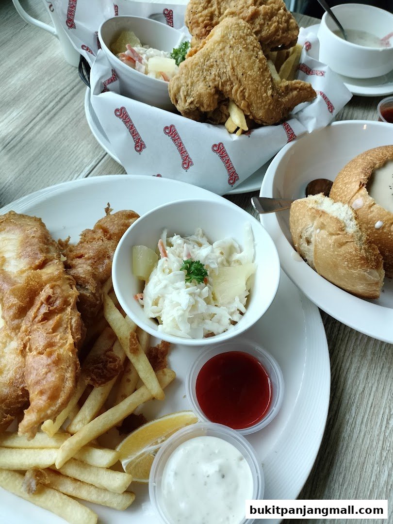 A close-up of Swensen's fried chicken and fish and chips with coleslaw and dipping sauces.