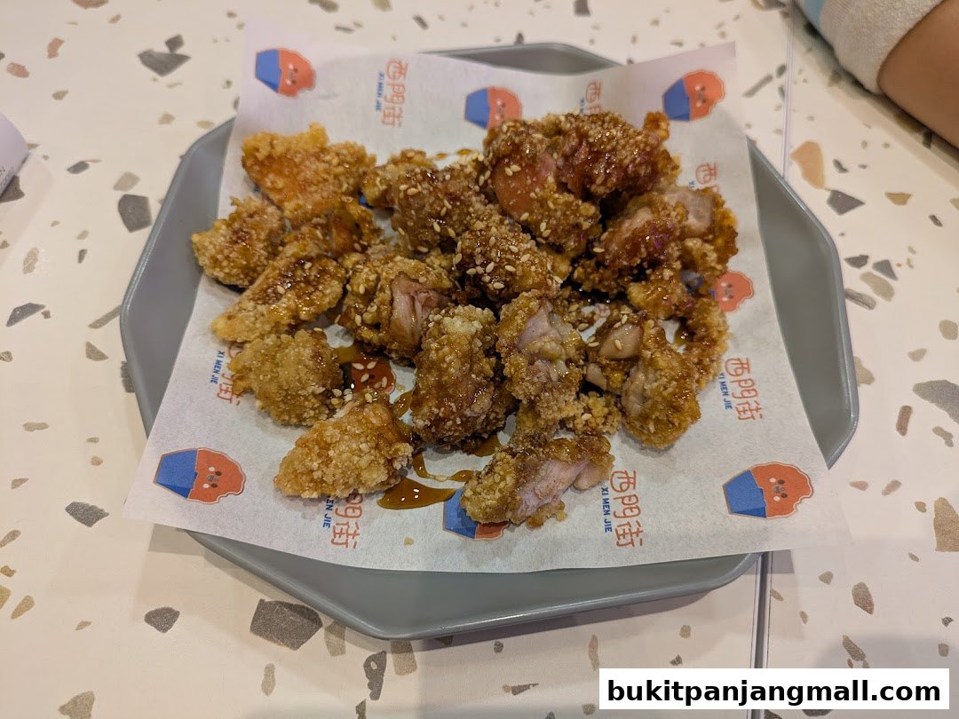 A plate of crispy, glazed Taiwanese fried chicken bites topped with sesame seeds.