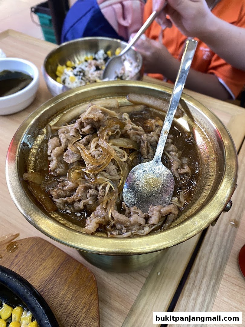 A close-up of a delicious Korean dish with tender beef and glass noodles in a golden bowl.