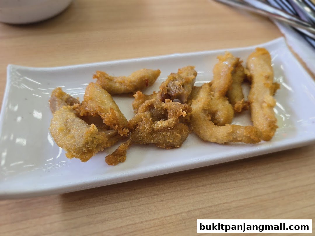 A white rectangular plate filled with golden-brown fried chicken pieces on a wooden table.