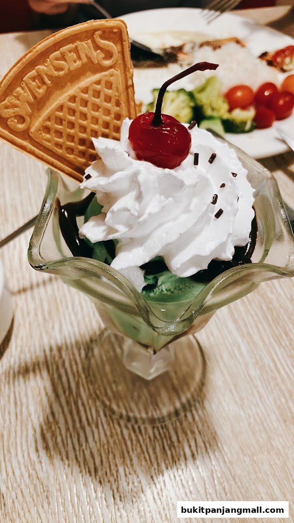 A delicious Swensen's ice cream sundae with whipped cream, cherry, and waffle.