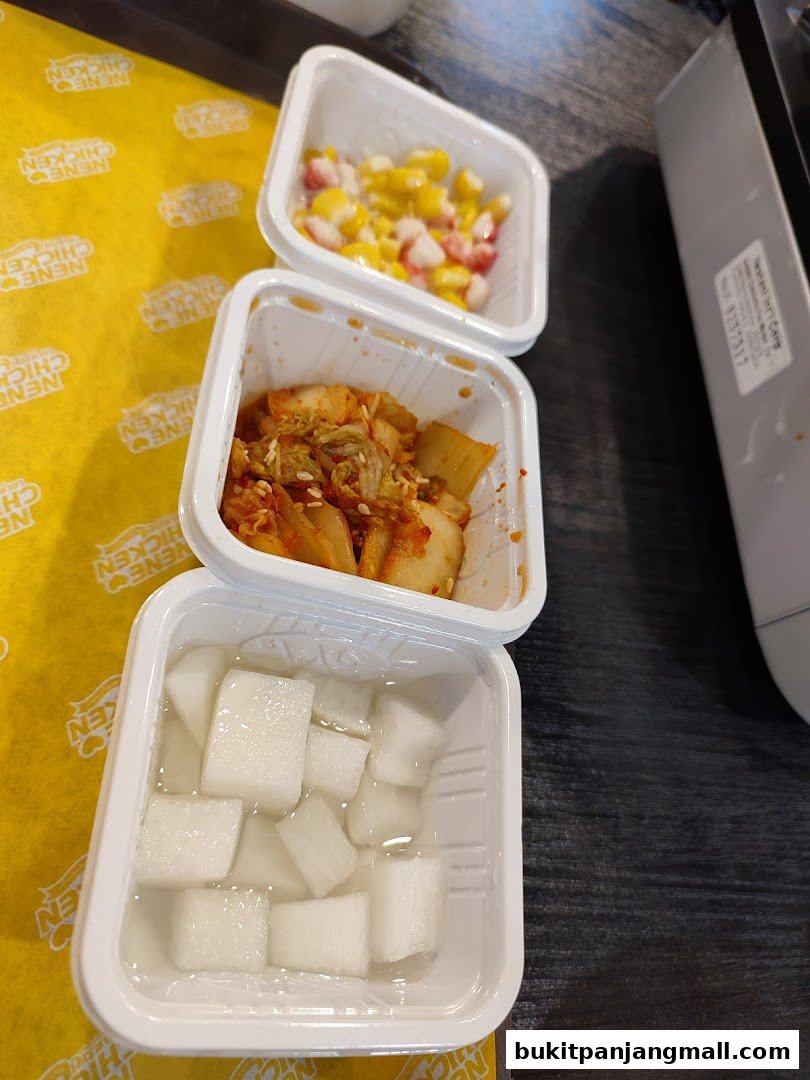 Three small containers of Korean side dishes, including kimchi, pickled radish, and corn salad.