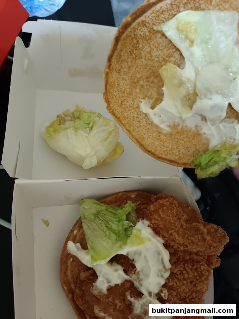 A close-up of two McDonald's burgers in their packaging, showing crispy chicken and fresh lettuce.