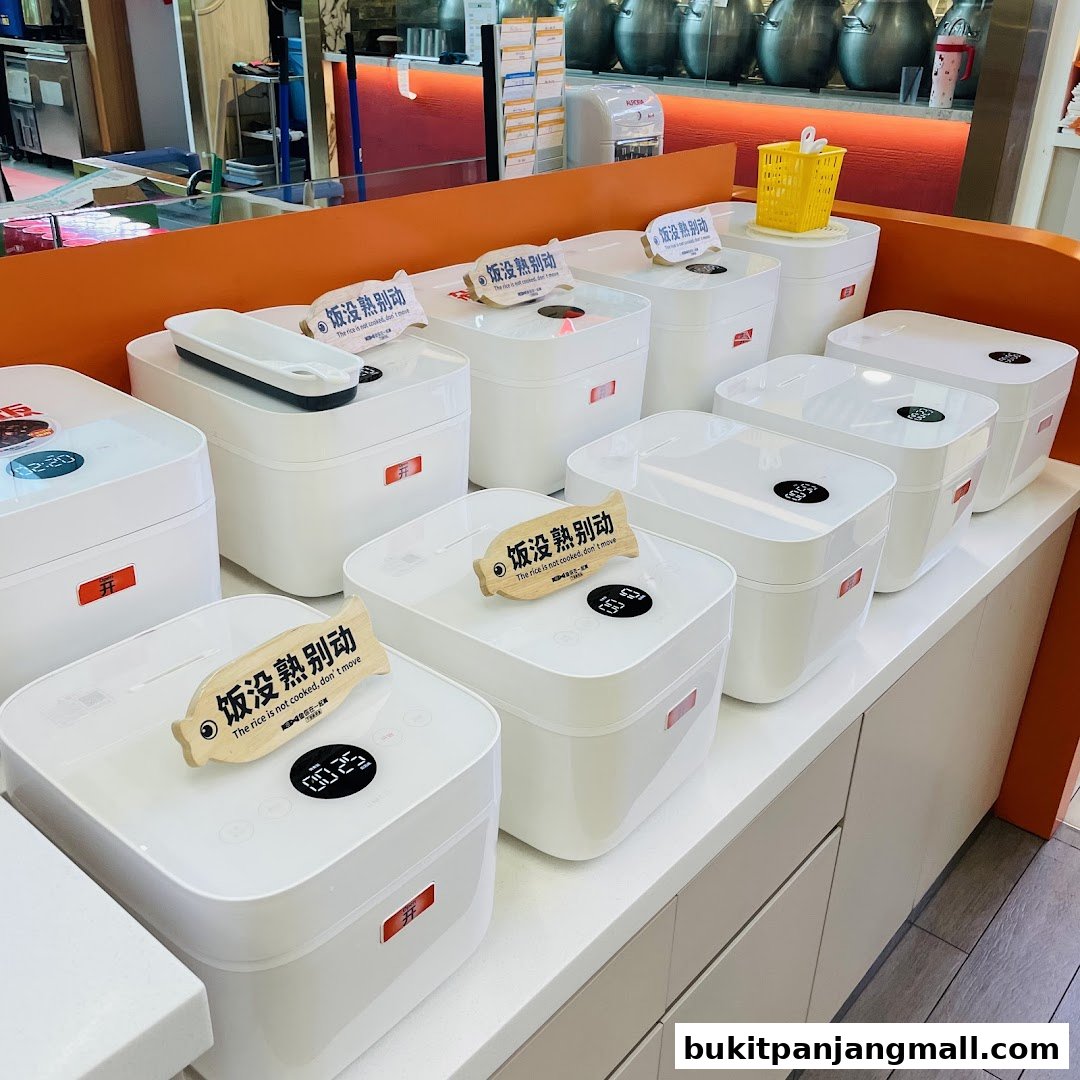 A display of white rice cookers with Chinese and English labels.