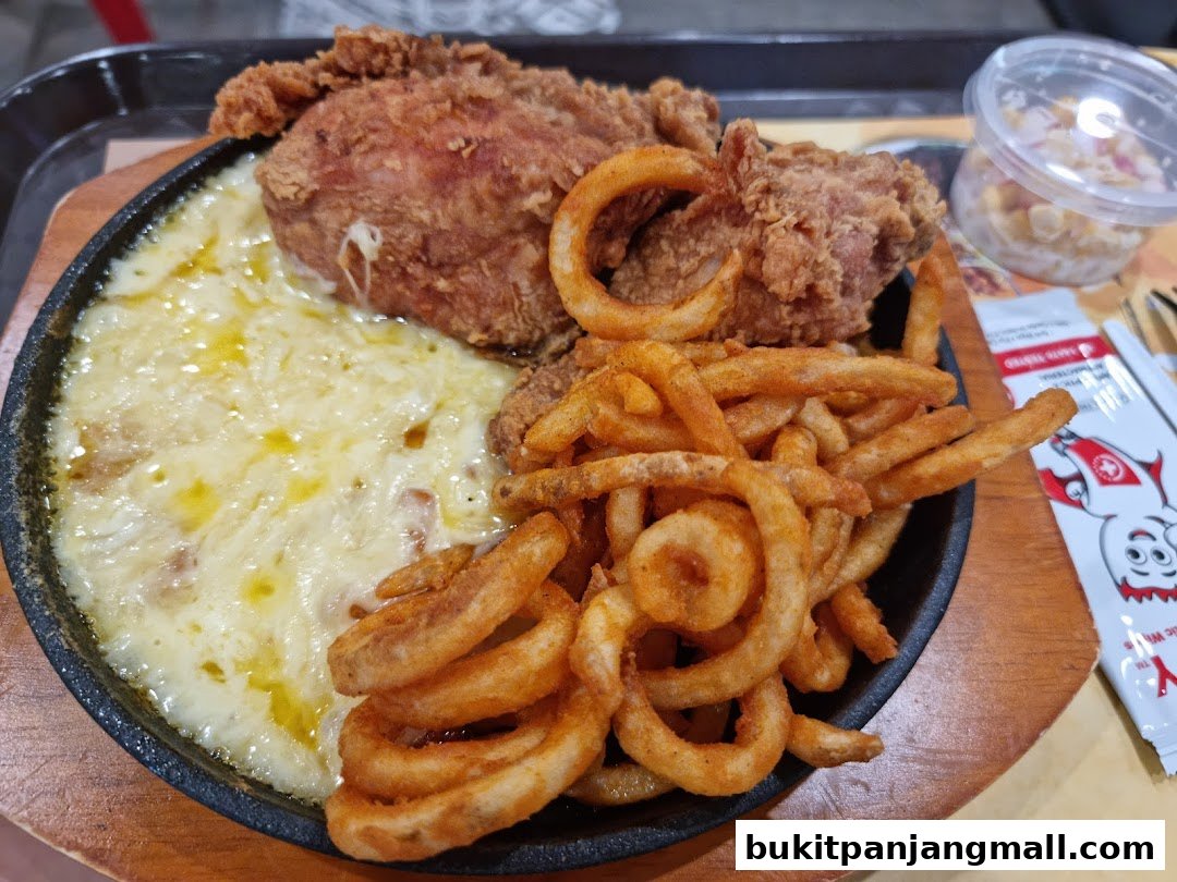 A sizzling platter of NeNe Chicken with melted cheese, curly fries, and a side of corn salad.