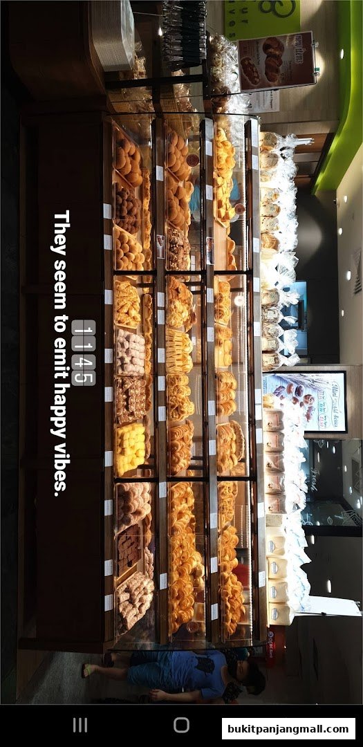 A display case filled with various baked goods, including breads and pastries, at a bakery.
