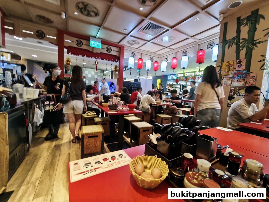 Interior of a busy ramen restaurant with customers dining and staff serving.