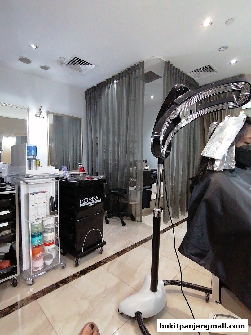 Interior of a hair salon with a client receiving treatment under a hair steamer.