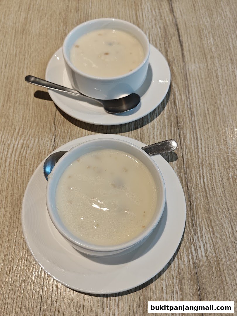 Two bowls of creamy soup with spoons on a wooden table.