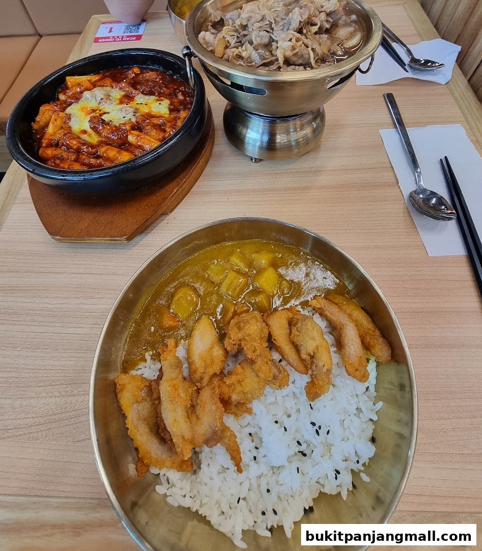 Three delicious Korean dishes served on a wooden table, including tteokbokki, beef stew, and fried chicken with rice.