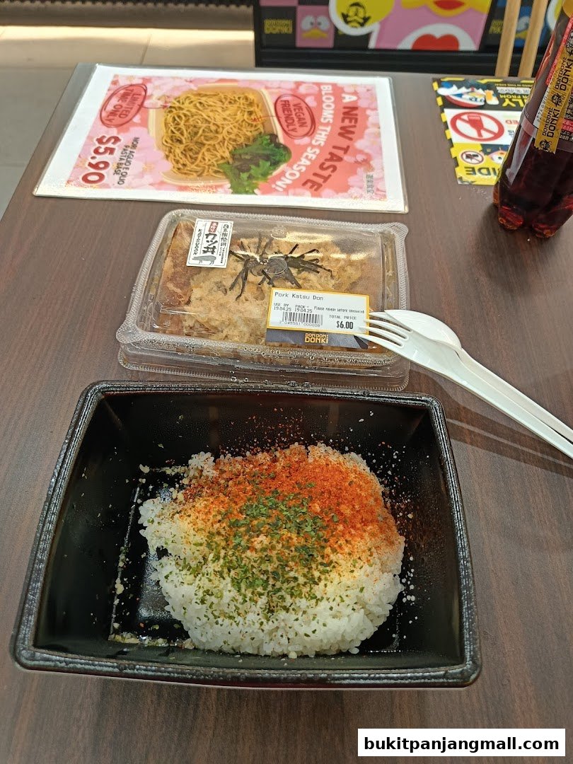 A table with Japanese food, including pasta, katsu don, and a drink.