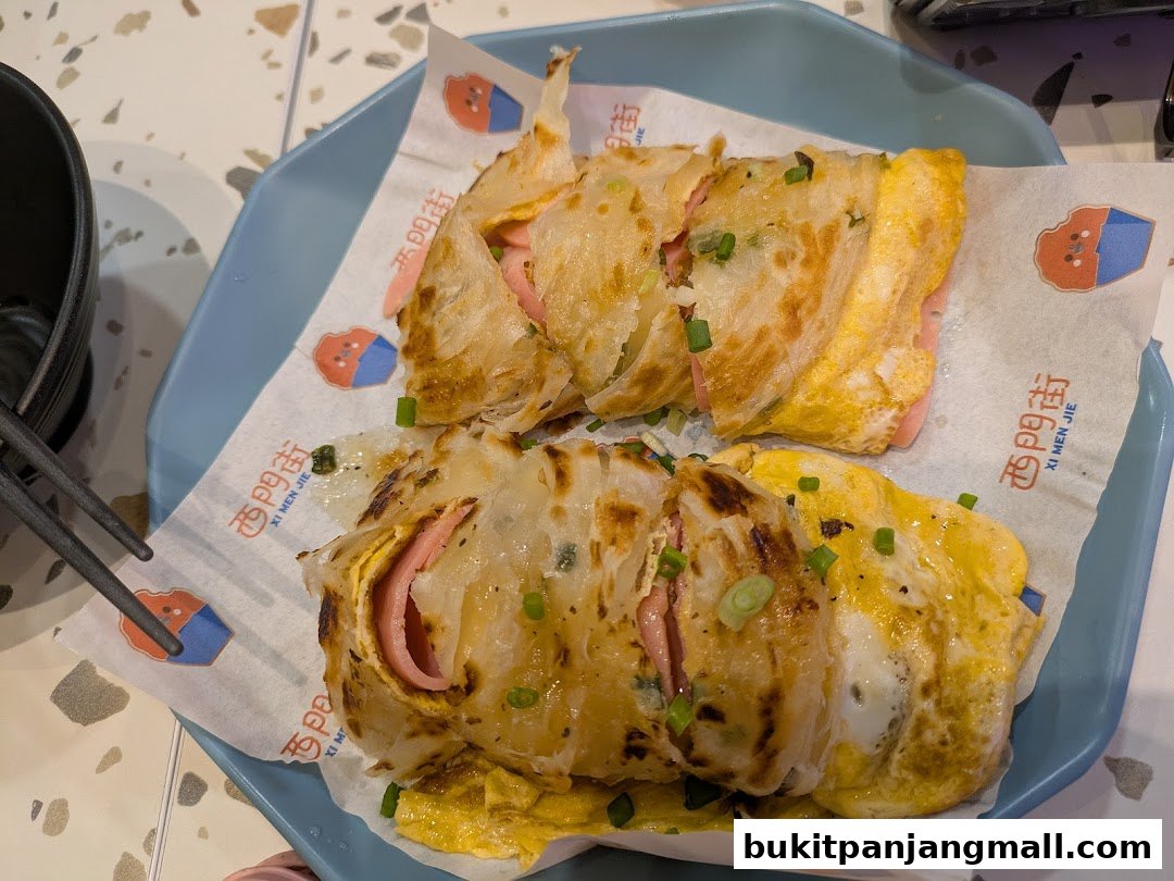 Two Taiwanese breakfast wraps filled with egg and ham, served on a blue plate.