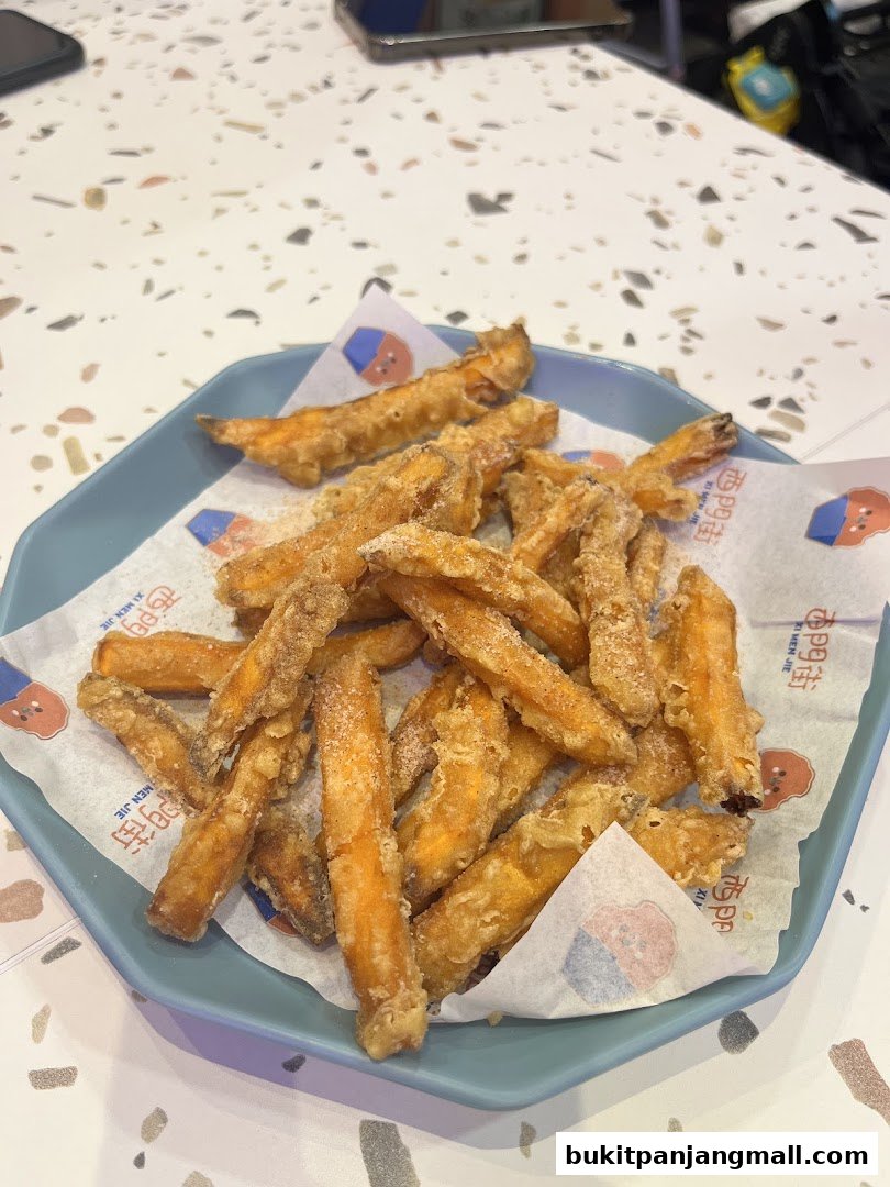 A plate of crispy fried sweet potato fries served on a blue plate with branded paper.