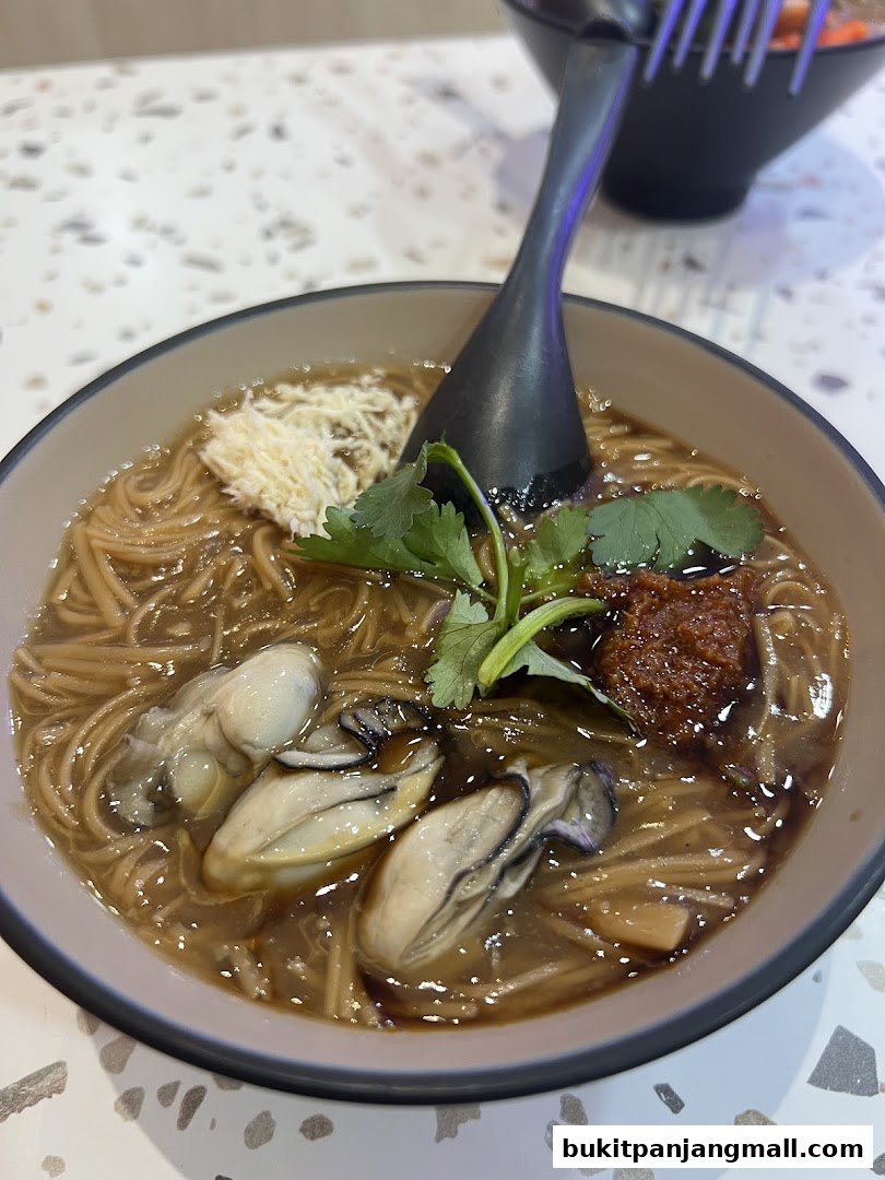 A close-up of a bowl of Taiwanese oyster omelet soup with noodles and cilantro.