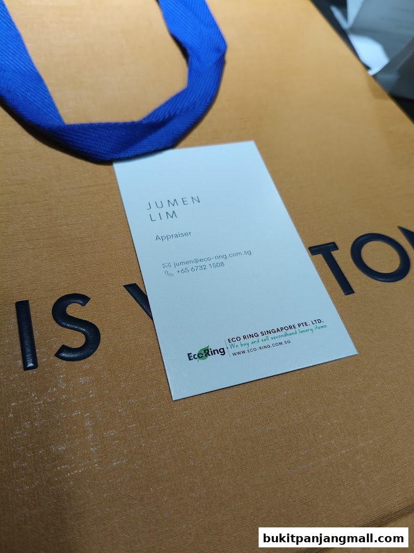 A business card from EcoRing Singapore is placed on a branded shopping bag.