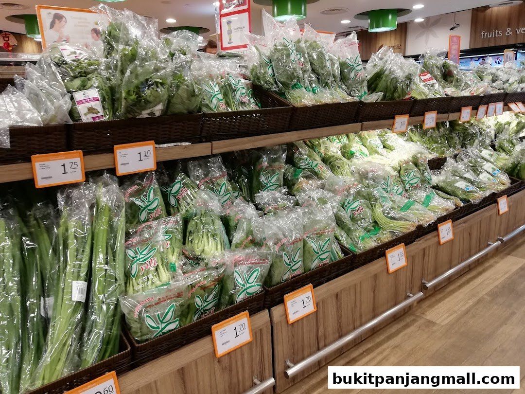 Fresh produce, including leafy greens and spring onions, neatly displayed on shelves at FairPrice Finest.
