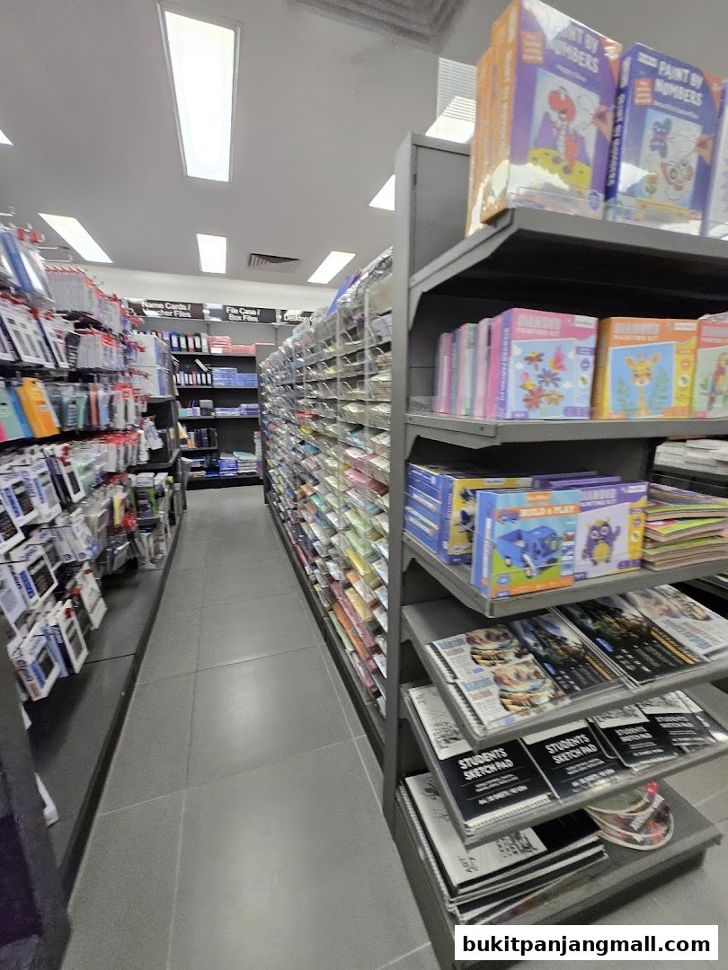 A wide aisle in a bookstore, showcasing shelves filled with stationery, art supplies, and books.
