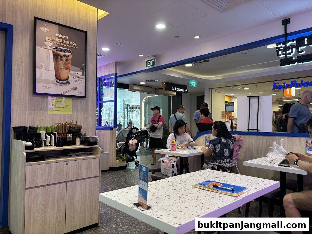 Interior of a Taiwanese food stall with customers seated at tables and a promotional poster on the wall.