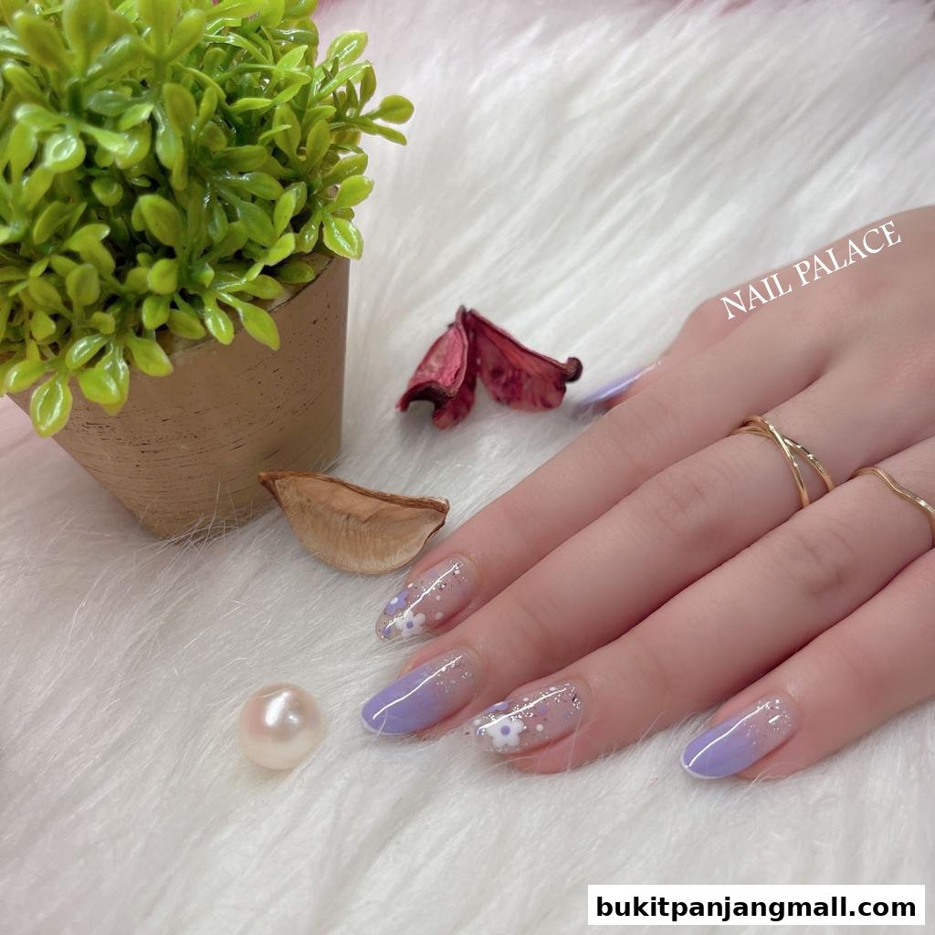A woman's hand with elegant lavender and floral nail art, adorned with rings.