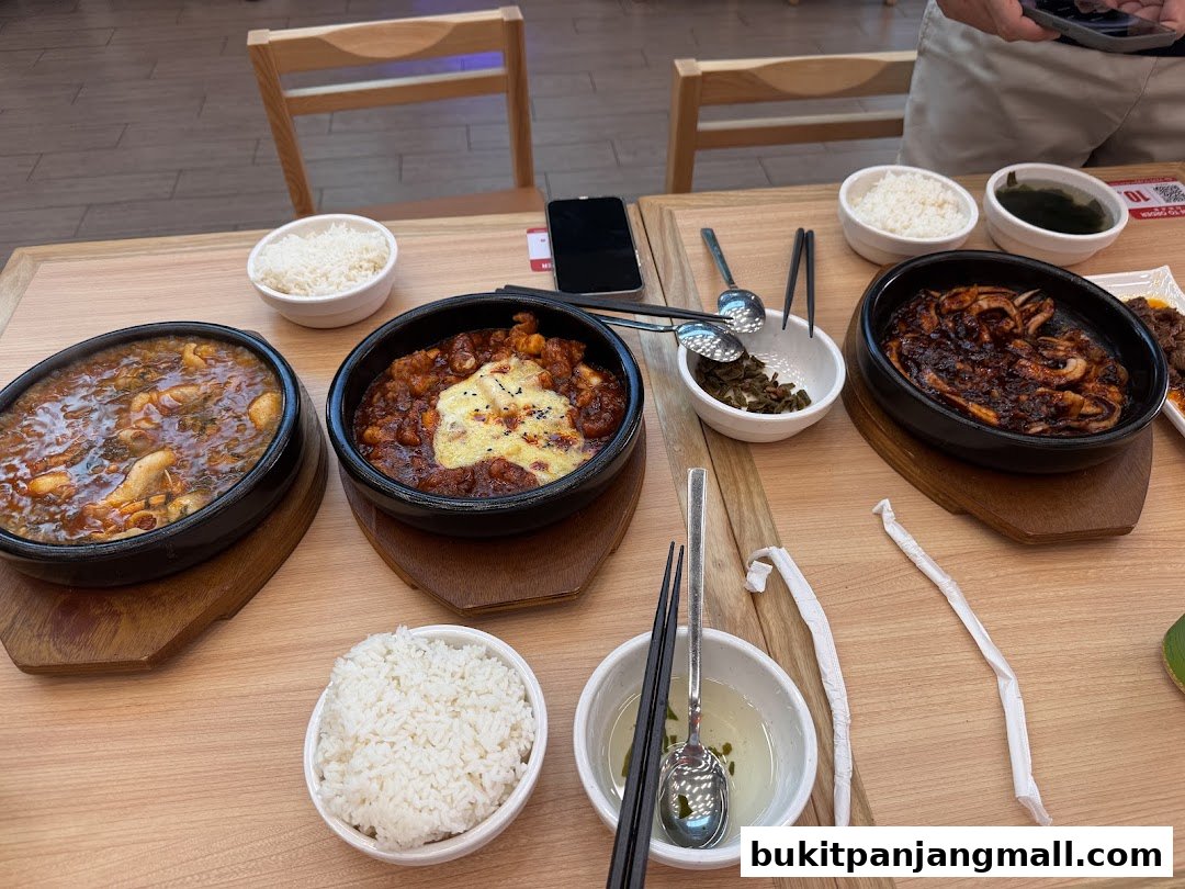 A table laden with Korean dishes, including bibimbap and rice, ready to be enjoyed.