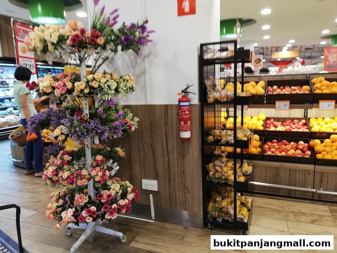 A display of colorful artificial flowers and fresh fruits in a supermarket.