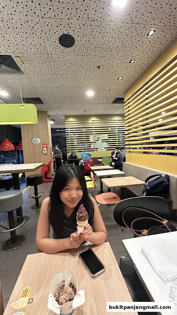 A young girl enjoys a chocolate ice cream cone inside a McDonald's restaurant.