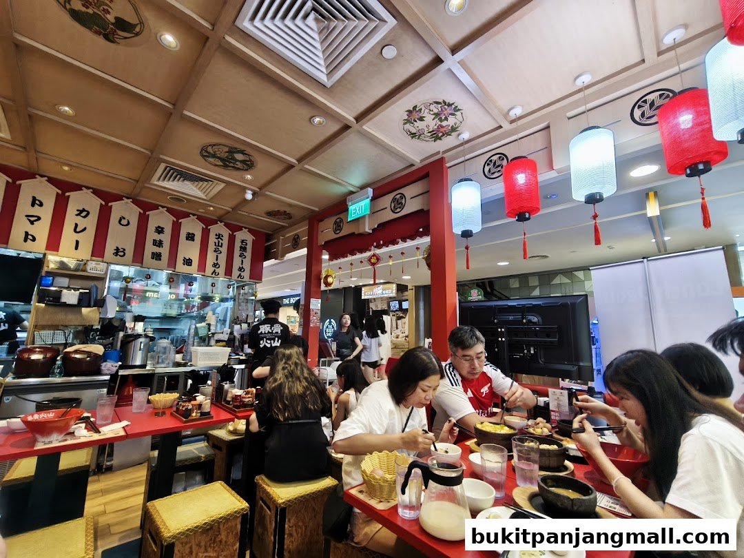 People dining at Tonkotsu Kazan, a Japanese restaurant with red tables and lanterns.