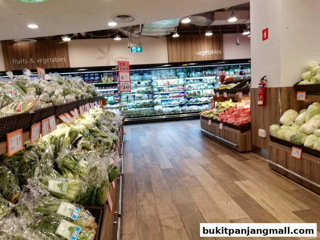 A wide aisle in a supermarket showcasing fresh produce, including leafy greens and vegetables.