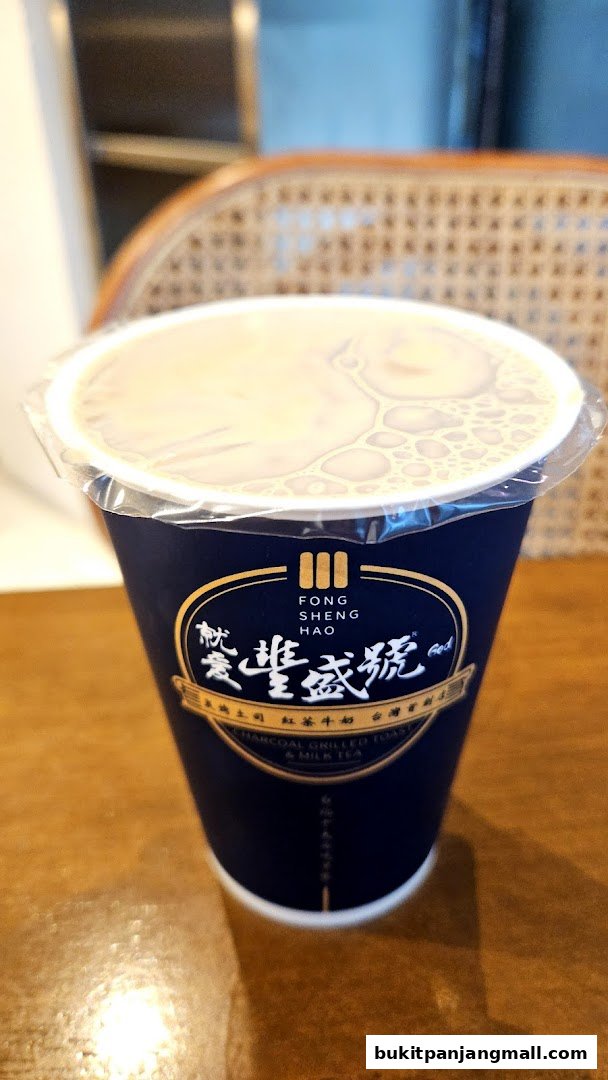 A close-up of a dark blue cup with the Fong Sheng Hao logo and text, containing a beverage.