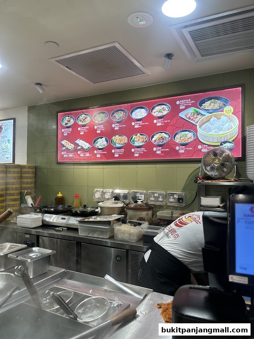 A brightly lit menu board displays various noodle and dumpling dishes with prices.