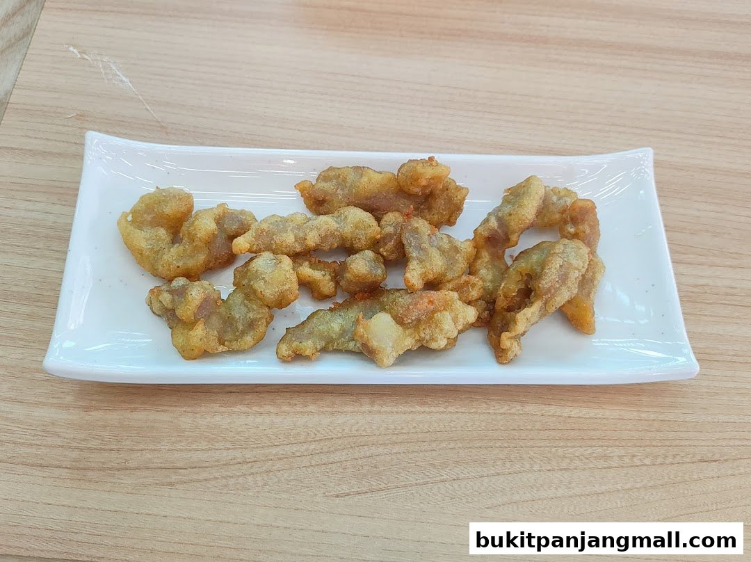 A white rectangular plate filled with golden-brown, crispy fried chicken pieces on a wooden table.