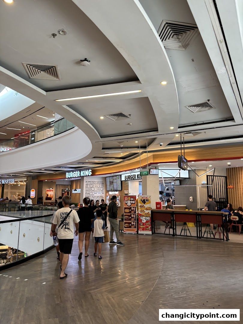 People walking past a Burger King restaurant in a shopping mall.