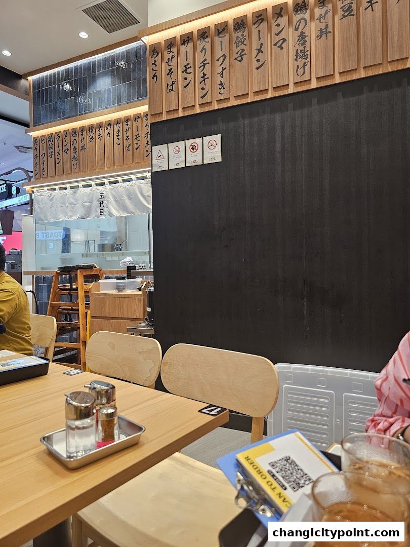 Interior of a Japanese restaurant with wooden menu boards and dining tables.