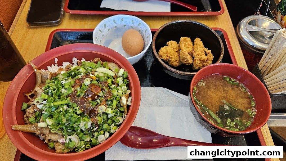 A delicious Sukiya Gyudon meal with fried chicken, egg, and miso soup.