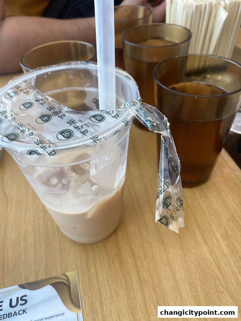 A close-up of a partially opened drink with a straw and several glasses of iced tea.
