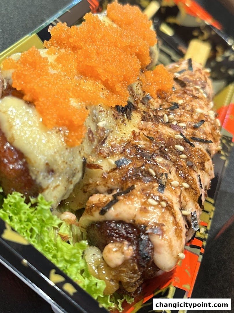 Close-up of a delicious salmon sushi roll topped with tobiko and sauce.