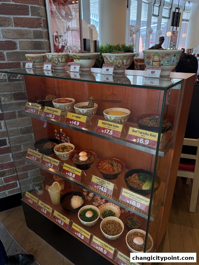 Display case showcasing various Japanese rice bowl dishes and drinks from Sukiya.