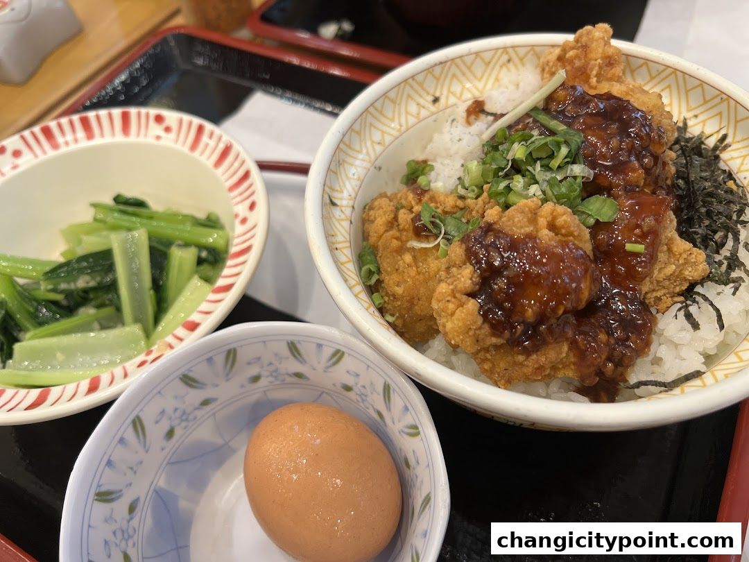 A close-up of a Sukiya Gyudon meal with fried chicken, rice, vegetables, and a boiled egg.